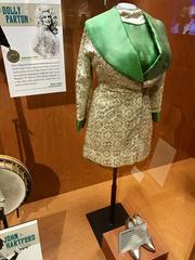 Dolly Parton's 1969 stage wear including brocade overwear and dress with brocade collar, and Renetti pumps, displayed at the Country Music Hall of Fame and Museum