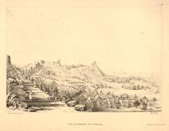 Stone steps leading to a figure standing on a fortified hill, overlooking houses and trees below in a lush landscape in India