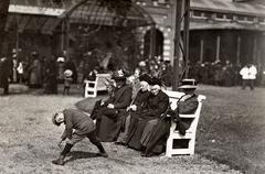 Visitors at Artis Zoo Amsterdam 1912, group of women in long dresses and coats sitting on a bench with a young boy standing in front