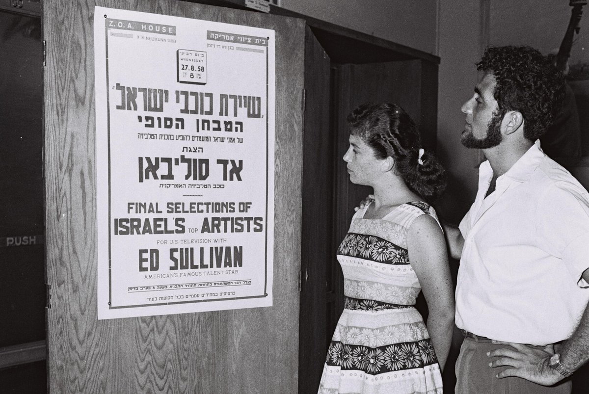 Nehama Handel and Ran (Menachem) Eliran looking at a show poster hosted by Ed Sullivan in 1958
