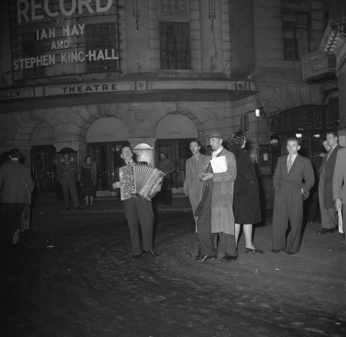 Accordion player performing at the exit of a theater in Soho, London in 1947