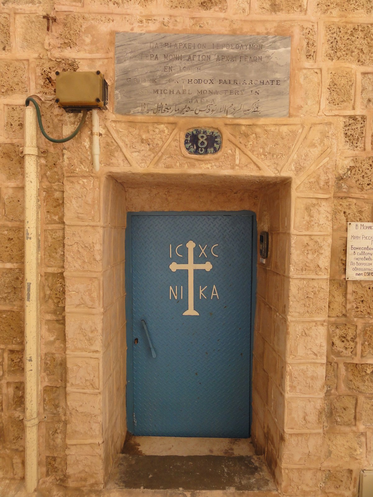 Blue metal door with Greek, English and Arabic inscriptions at St. Michael Monastery in Jaffa