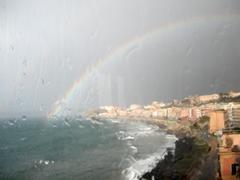 Rainbow over the waterfront of Pozzuoli with Rione Terra in the background seen through glass distortion