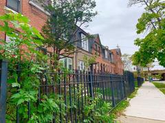 Red brick row homes with black iron fences and mowed grass yards in Pullman, Chicago