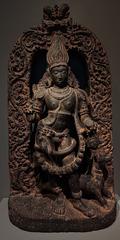 Fierce form of the Hindu deity Shiva as Bhairava with flame-like hair, bulging eyes, fangs, cobra, garland of skulls, and accompanying dog