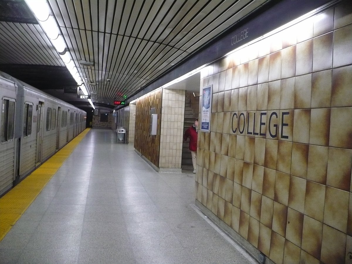 Northbound platform of College TTC subway station with train and passengers