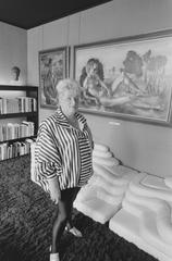 Dutch businesswoman Miep Brons standing in front of three artworks in her house