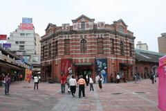 Red theater building in Taipei at night with illuminated windows and trees around