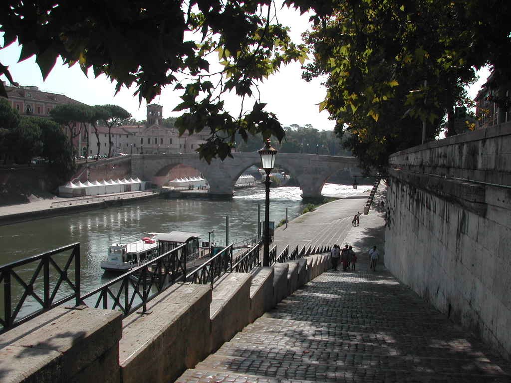 Boat boarding on the Tiber River in Rome near Lungotevere degli Anguillara with Ponte Cestio and Tiber Island in the background