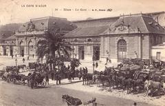 Old postcard of Nice train station in France with steam locomotives and people on platform