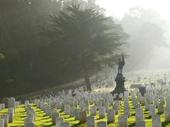 National Cemetery in Presidio of San Francisco with rows of white headstones and green grass under a cloudy sky