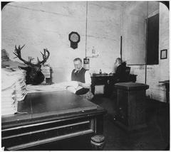 Historic photograph of San Francisco Mint employees with mounted deer head in basement office