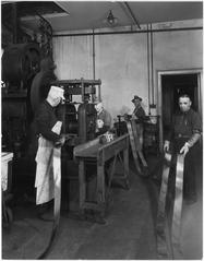 Black and white photograph of rolling bullion into strips at a metalworking factory