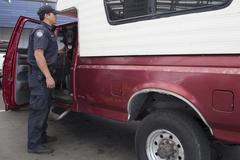 U.S. Customs and Border Protection officer with canine inspecting vehicles at San Ysidro border crossing