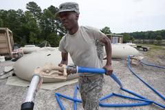 U.S. Army Sgt. William White carrying hose to fill water supply tank during Ardent Sentry 2013 exercise