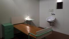 Interior view of a hospital room in Paimio Sanatorium with wooden furniture and green curtains