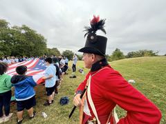 Living historians and park rangers talking about flags with children at Patterson Park