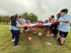 Children opening a large 30 by 42 feet American flag at Patterson Park
