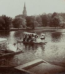 Swan boats on lake in Boston Public Garden with church steeple in background