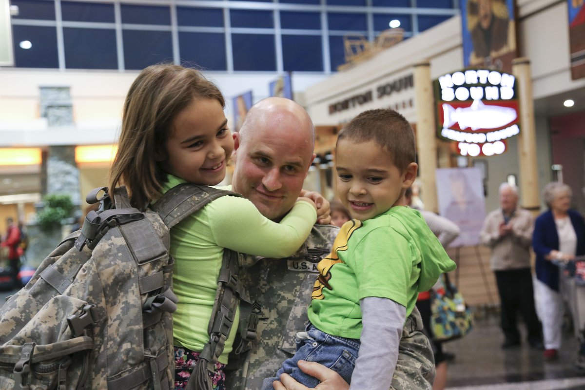 Alaska Army National Guardsman holding his children after deployment
