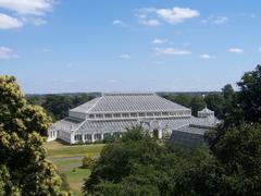 Landscape view of Kew Gardens with a historic glasshouse and lush greenery