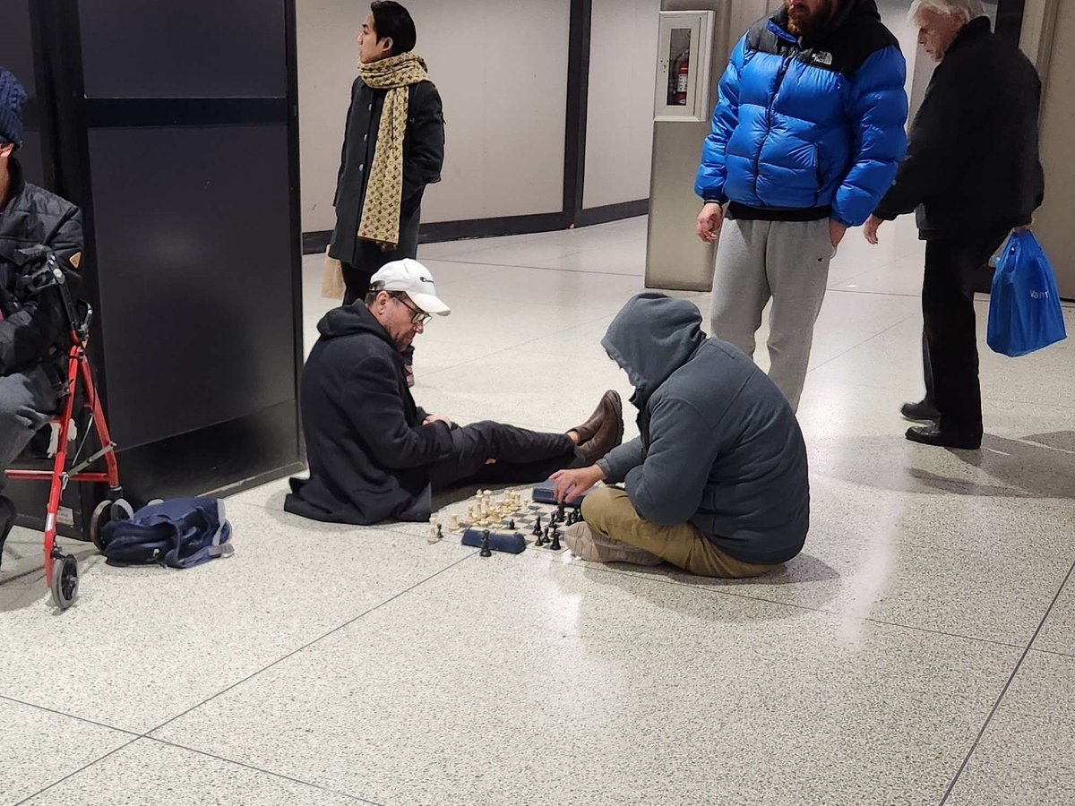 Two men playing chess on the floor at North York Centre TTC Station in Toronto