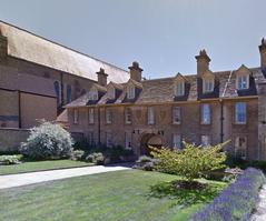 Sommerville College Darbishire Quad with historic red brick buildings and lush green lawn under clear blue sky