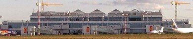 Aerial view of Bari Airport airside with airplanes and terminal buildings under clear blue sky