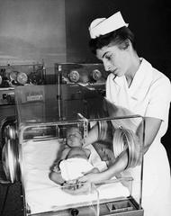 Newborn baby in incubator held by nurse at Toronto Western Hospital