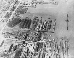 Aerial view of the Union Iron Works shipyard in San Francisco, California during World War I showing four-piper destroyers, submarines, and merchant ships under construction and docked at various facilities including foundries, machine shops, wharves, and floating docks labeled with detailed plant features