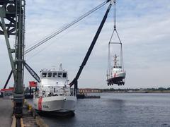 Coast Guard Cutter Albacore being lowered into water near moored Coast Guard Cutter Chinook at Baltimore Coast Guard Yard
