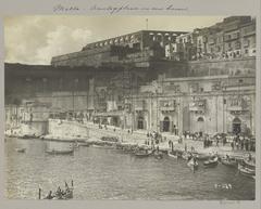Historic view of a harbor quay in Malta with vintage vehicles and ships around 1900
