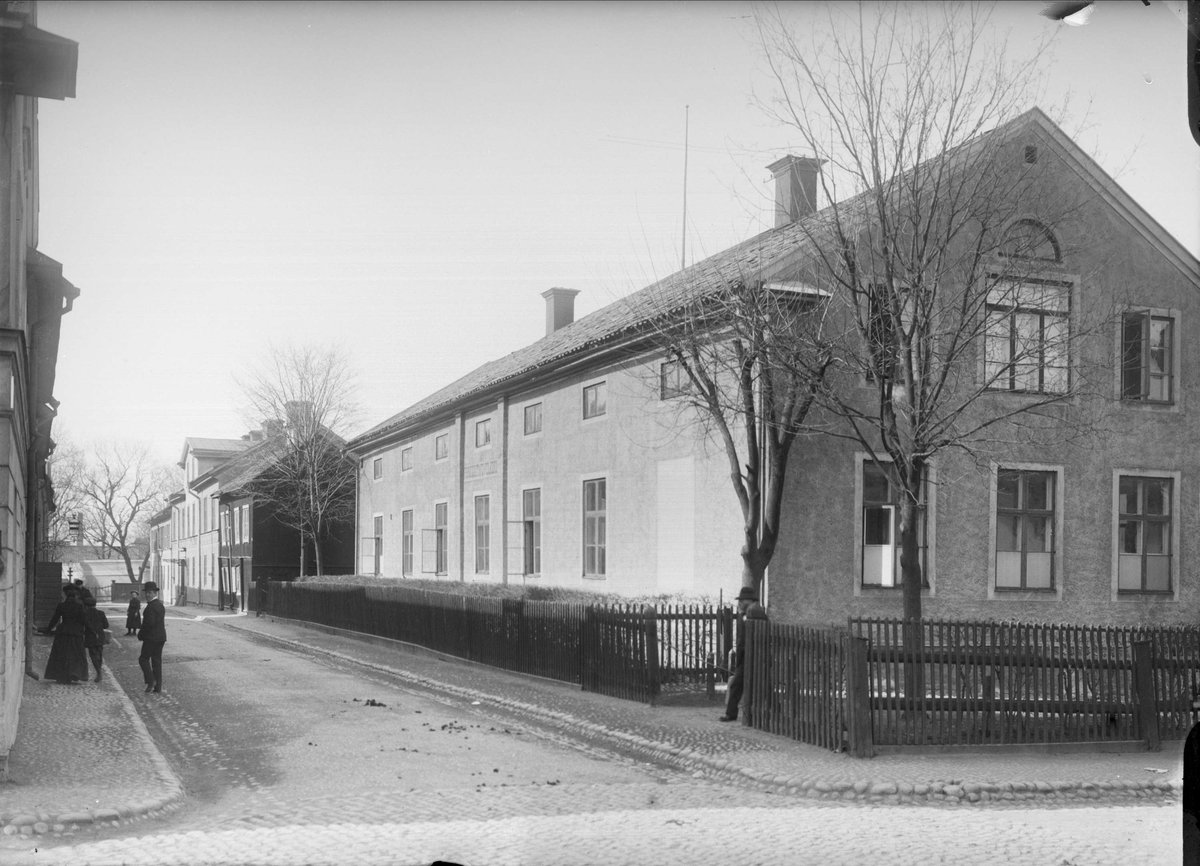Historic street view of Dragarbrunnsgatan north from Järnbrogatan in Uppsala with 19th-century school building
