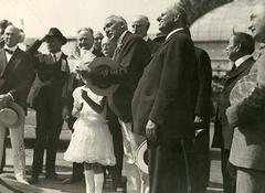 President Warren G Harding with young girl holding kite string surrounded by small group of men in Volunteer Park Seattle