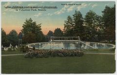 Children playing in a playground and wading pool in Volunteer Park around 1915 with vintage play structures and children in period clothing