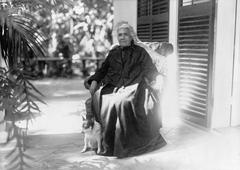 Liliuokalani seated outdoors with her dog Poni, facing slightly left