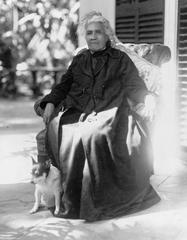 Full-length portrait of Queen Liliuokalani seated outdoors with her dog Poni, facing slightly left