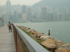 People fishing at West Kowloon Waterfront Promenade in Hong Kong with city skyline in the background