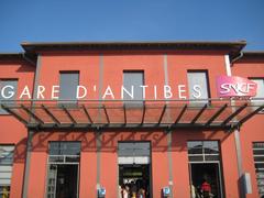 Antibes train station exterior with signage and parked cars