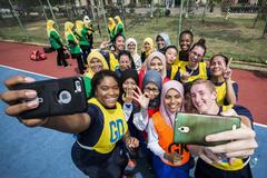 U.S. Navy personnel and International Islamic University of Malaysia students taking group photos on phones after a netball game during Pacific Partnership 2016 community event in Kuantan