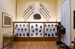 Collection of historical weapons and armor including polearms, Venetian consulate emblem, helmets, cuirasses, suit of armour, marine couleuvrines, and cannon projectiles from 14th to 19th century