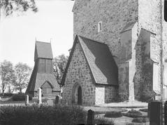 Gamla Uppsala Church exterior view with wooden bell tower in the background