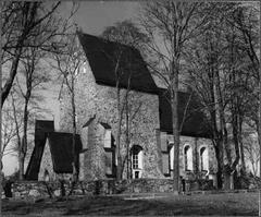Southwest view of Gamla Uppsala Church, a historic stone church with a tall tower and green surroundings