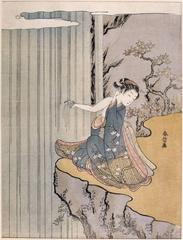 Woman sitting on cliff edge touching waterfall water