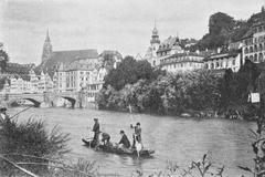 View of Neckar river in Tübingen with a Stocherkahn boat, old Eberhardsbrücke bridge, Schnaith'sches Haus at Neckartor, historic old town and Stiftskirche church