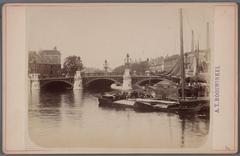 New stone Blauwbrug bridge over the Amstel River viewed westward with diamond polishing factories on the right