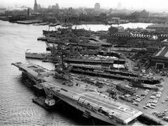 Aerial view of the U.S. Navy Boston Naval Shipyard in Massachusetts on 1 April 1960 showing various ships including USS Wasp aircraft carrier, USS Macon heavy cruiser, USS Hugh Purvis destroyer and others at multiple piers and dry docks