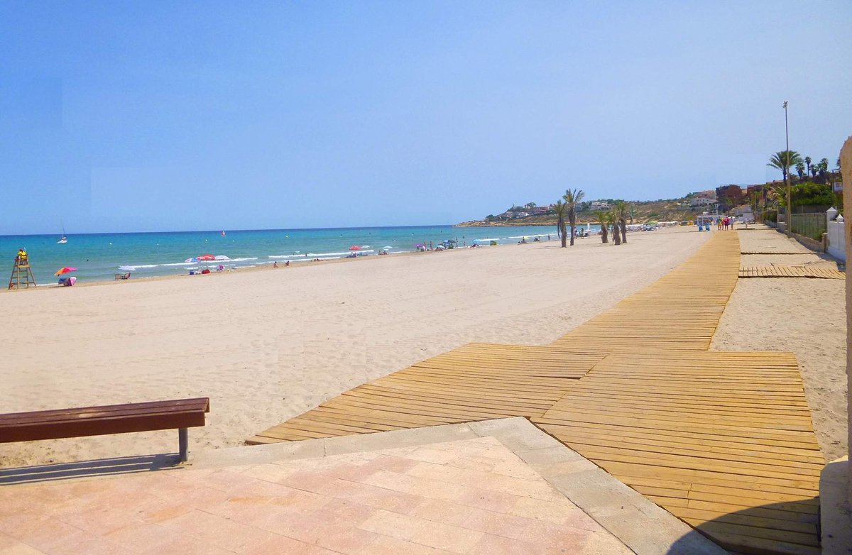 Panoramic view of Playa de San Juan beach in Alicante with golden sand and gentle waves under a blue sky