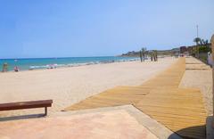 Panoramic view of Playa de San Juan beach in Alicante with golden sand and gentle waves under a blue sky
