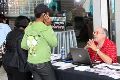 Visitors at the CommUnity Resource and Information Festival in Texas interacting with FEMA representative Pedro Bernardini